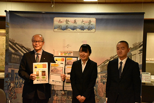 贈呈された展示解説シートを手にする尾崎勝会長と学生