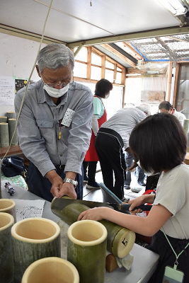 竹をノコギリで切る参加者