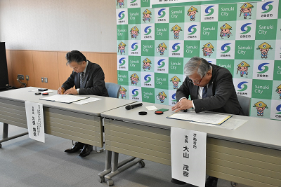 協定書に調印する大山市長と久保取締役